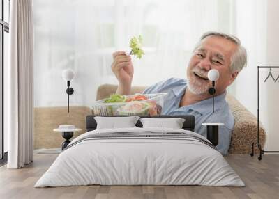 Lifestyle senior man feel happy enjoy eating diet food fresh salad on sofa Wall mural