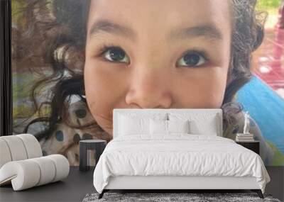 Portrait of a cute little girl with curly hair looking at camera Wall mural