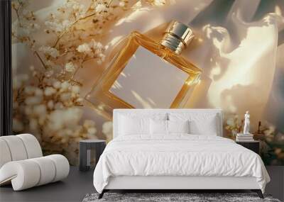 A close-up of a perfume bottle with a blank label, nestled in soft white fabric, surrounded by delicate flowers and a subtle golden hue Wall mural