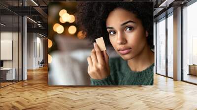 Woman gently placing an adhesive bandage on her finger in a cozy home, showcasing self-care and safety at home. Wall mural