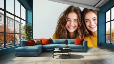 Two young women smiling together, wearing matching outfits, bright atmosphere. Wall mural