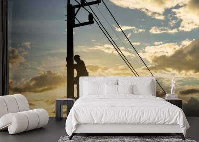 Silhouette man works with electricity on a pole with the sunset in the sky. Wall mural