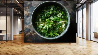 A bowl of aromatic soup topped with fresh herbs and greens. Wall mural