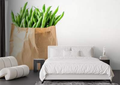 A brown paper bag filled with fresh green beans against a light background. Wall mural