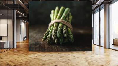 A bundle of fresh asparagus tied with twine on a rustic wooden surface. Wall mural