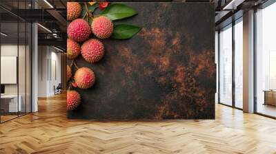 A cluster of lychee fruits with green leaves on a textured surface. Wall mural