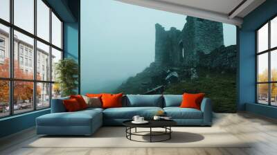 A misty landscape featuring the ruins of a stone castle on a hillside. Wall mural