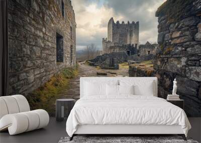 A scenic view of ancient ruins with stone walls and a castle under a cloudy sky. Wall mural