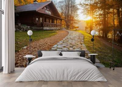 A serene pathway leading to a rustic cabin at sunset, surrounded by autumn foliage. Wall mural