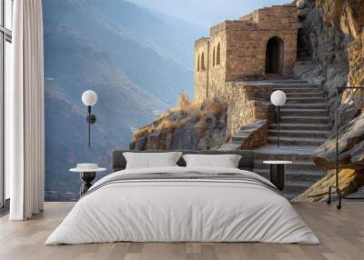 A stone structure perched on a mountainside with steps leading up to it. Wall mural