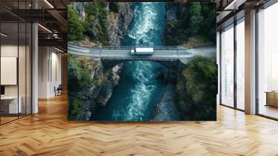 Aerial view of a truck crossing a bridge over a rushing river surrounded by lush greenery. Wall mural