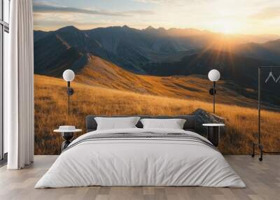 Serene mountain landscape at sunset with golden grass and distant peaks. Wall mural