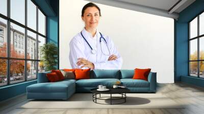 Femal doctor in white gown with stethoscope looking at camera in self-confidence manner Wall mural