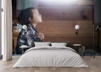 asian little girl reading and praying on bible in morning at home. christian concept. Wall mural