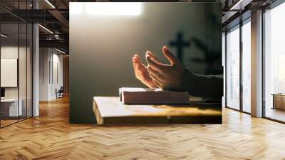 Christian hands praying on holy bible in light of morning at wooden table. christian concept. Wall mural