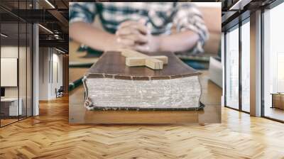 Close up the old Bible and wooden cross with young male praying on guitar acoustic at background. Christian worship God concept. Wall mural