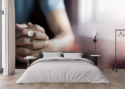 Hands folded in prayer on wooden table in church, concept for faith, spirituality and religion, a man praying in the morning. close up hands praying, with copy space , space for text. Wall mural