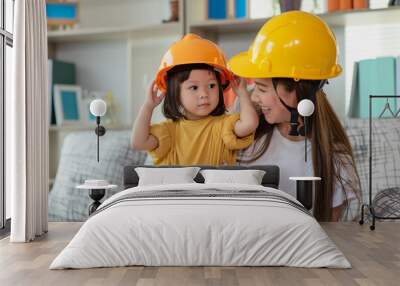 Asian mother and her daughter wearing yellow engineer helmet, education and occupation concept Wall mural