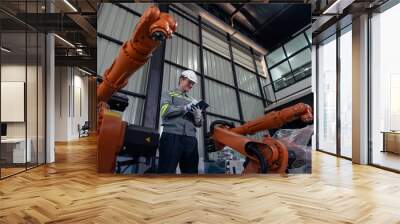 Engineer standing by robotic arm and operating machine in industry factory, technician worker check for repair maintenance electronic operation Wall mural