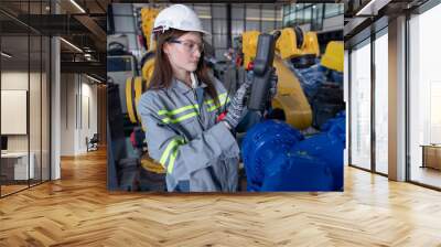 Engineer standing by robotic arm and operating machine in industry factory, technician worker check for repair maintenance electronic operation Wall mural