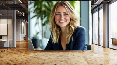 A businesswoman with a positive expression uses her laptop in a stylish, sunlit office. Wall mural