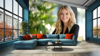 A businesswoman with a positive expression uses her laptop in a stylish, sunlit office. Wall mural