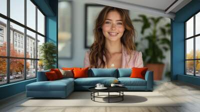 A cheerful young woman in stylish attire beams as she holds a contemporary vintage trophy, her smile and relaxed demeanor showcasing success. Wall mural