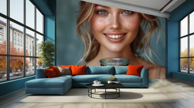 A cheerful young woman in stylish attire beams as she holds a contemporary vintage trophy, her smile and relaxed demeanor showcasing success. Wall mural