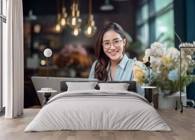 A happy Asian office girl working on her laptop in a cozy cafe, with a blurred background adding to the serene atmosphere. generative Ai. Wall mural