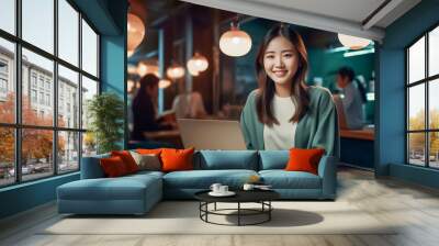 A happy Asian office girl working on her laptop in a cozy cafe, with a blurred background adding to the serene atmosphere. generative Ai. Wall mural