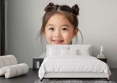 A happy little Asian girl dressed in a white t-shirt, smiling warmly at the camera. Her clean and simple look, combined with her joyful demeanor, makes this photo ideal for advertisements, Wall mural