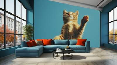 A orange cat jumps against a bold blue backdrop, exuding a sense of joy and vitality in its playful movement. Wall mural