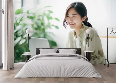 A Smiling Asian Woman working with her laptop in front of light cream background. generative AI. Wall mural