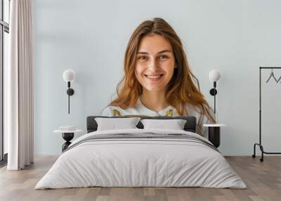 A smiling young caucasian woman in a casual attire holds a gold trophy, her eyes shining with pride. The image captures the essence of victory and the rewards of dedication. Wall mural