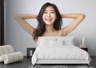 A young and pretty woman in a white underwear dress exudes joy and relaxation, raising her arms wide with a cute smile, revealing her smooth armpits against a pristine white background. Generative AI. Wall mural