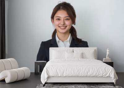 Adorned in stylish blue business attire, a jubilant Japanese girl beams with joy as she proudly holds a gold trophy against a white background. Wall mural