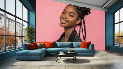 An African American woman with a warm smile and braided hair against a pink background. Her glowing skin and joyful expression emphasize her natural beauty. Wall mural