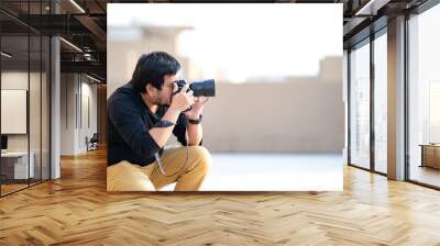 Asian Professional Camera man looks in to camera viewfinder and focus on the view for take a photo at rooftop outdoor field. Wall mural