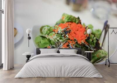 Green vegan salad from green leaves mix and vegetables, top view on white table. Green salad, close up by green vegetable, seaweed, and tobiko dressing on a white plate, isolated on white background. Wall mural