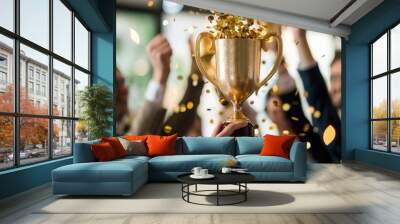 New win award trophy of Victorious business team in office environment, holding aloft a gleaming gold trophy, colleagues cheering and applauding in blurred background. Wall mural