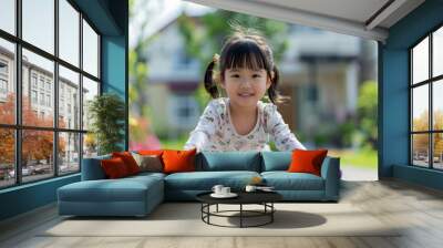 Riding her bike through the neighborhood streets, a happy Asian girl enjoys the sunny day, her house blurred in the background. Wall mural