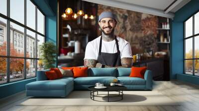 The portrait of a male chef, wearing white T-shirt and black apron, standing in a kitchen restaurant at night, Generative AI. Wall mural