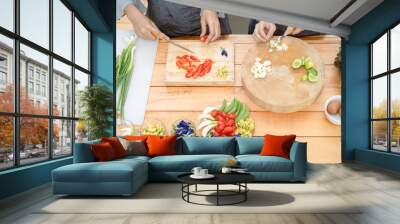 Two Asian female cut garlic and tomato by knife on the wood board with half lime cowslip flower butterfly pea spring onion peas and eggs in that area then preparing for lunch. Wall mural