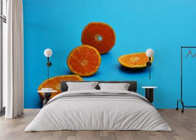 An orange fruit cut into four parts on blue  background Wall mural