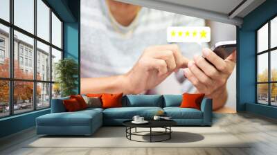 Customer pressing on smartphone with five star icon for feedback review satisfaction service Wall mural