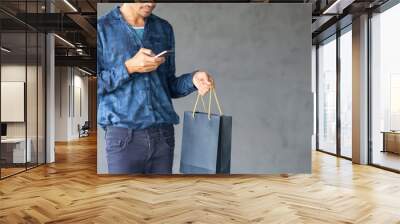 Lifestyle man using mobile phone and holding shopping bag with copy space gray wall background, Application online shopping design banner concept Wall mural