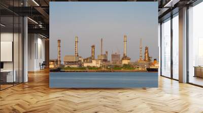 Crude oil refinery plant and many chimney with petrochemical tanker or cargo ship at coast of river on sky afternoon  bright day at thailand Wall mural