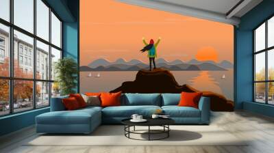 woman stands at the top of the mountain happily. There are sea, mountains and sunset background Wall mural