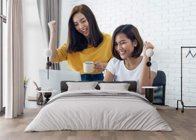 Two young asian woman working  laptop computer on wood desk in Home office Wall mural