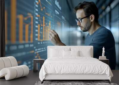 Focused man analyzing data on a futuristic digital screen, representing technology and data analysis in a modern workspace. Wall mural